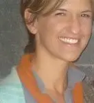 A woman smiling for the camera with her hair in front of a wall.