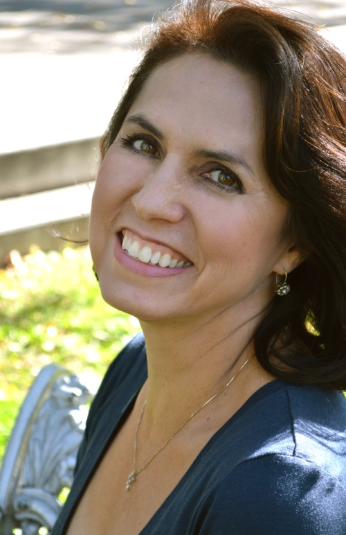 A woman with brown hair and green eyes smiling.